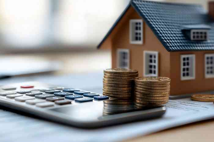 Kleines Häuschen mit Taschenrechner und Münzen - © VINA - stock.adobe.com